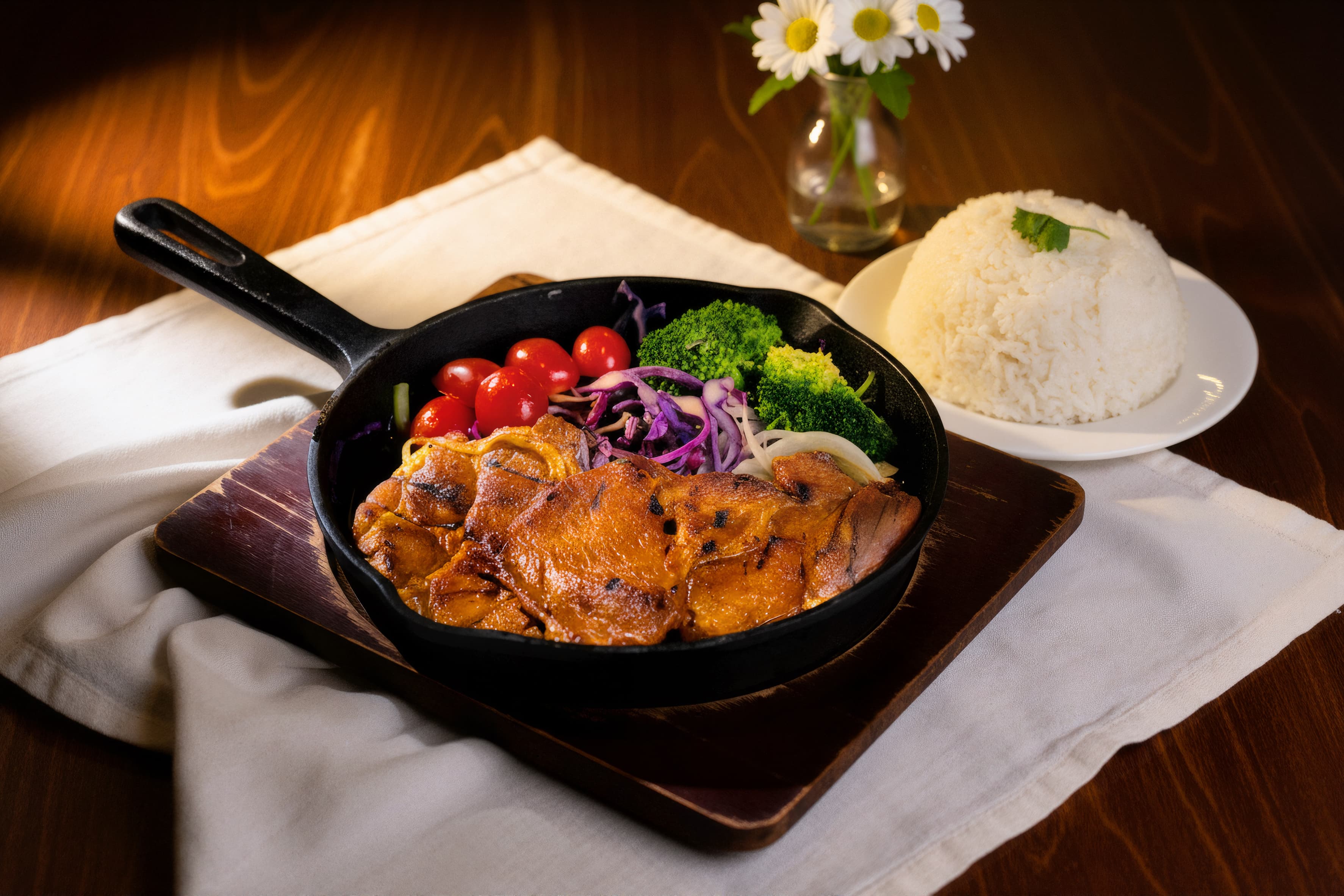 Flame-grilled chicken chop in a skillet with steamed rice